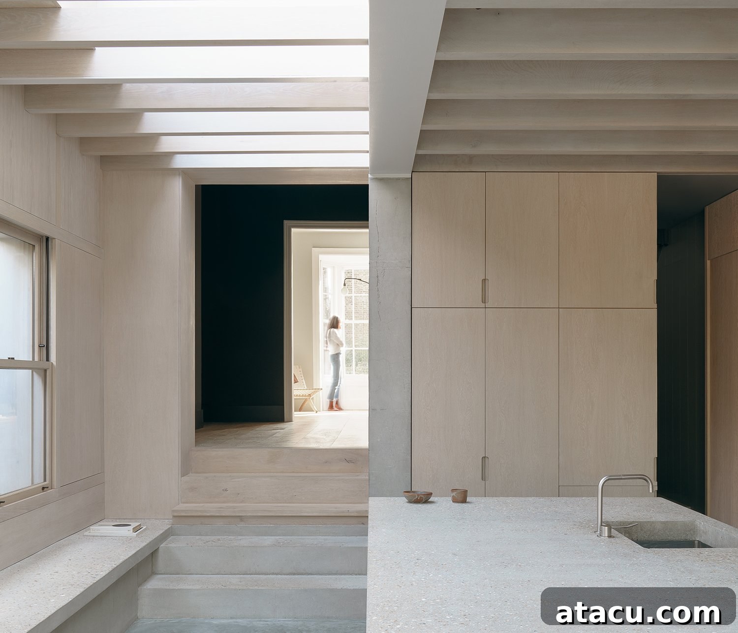 Wide shot of the modern kitchen with concrete and light wood elements under beamed ceiling