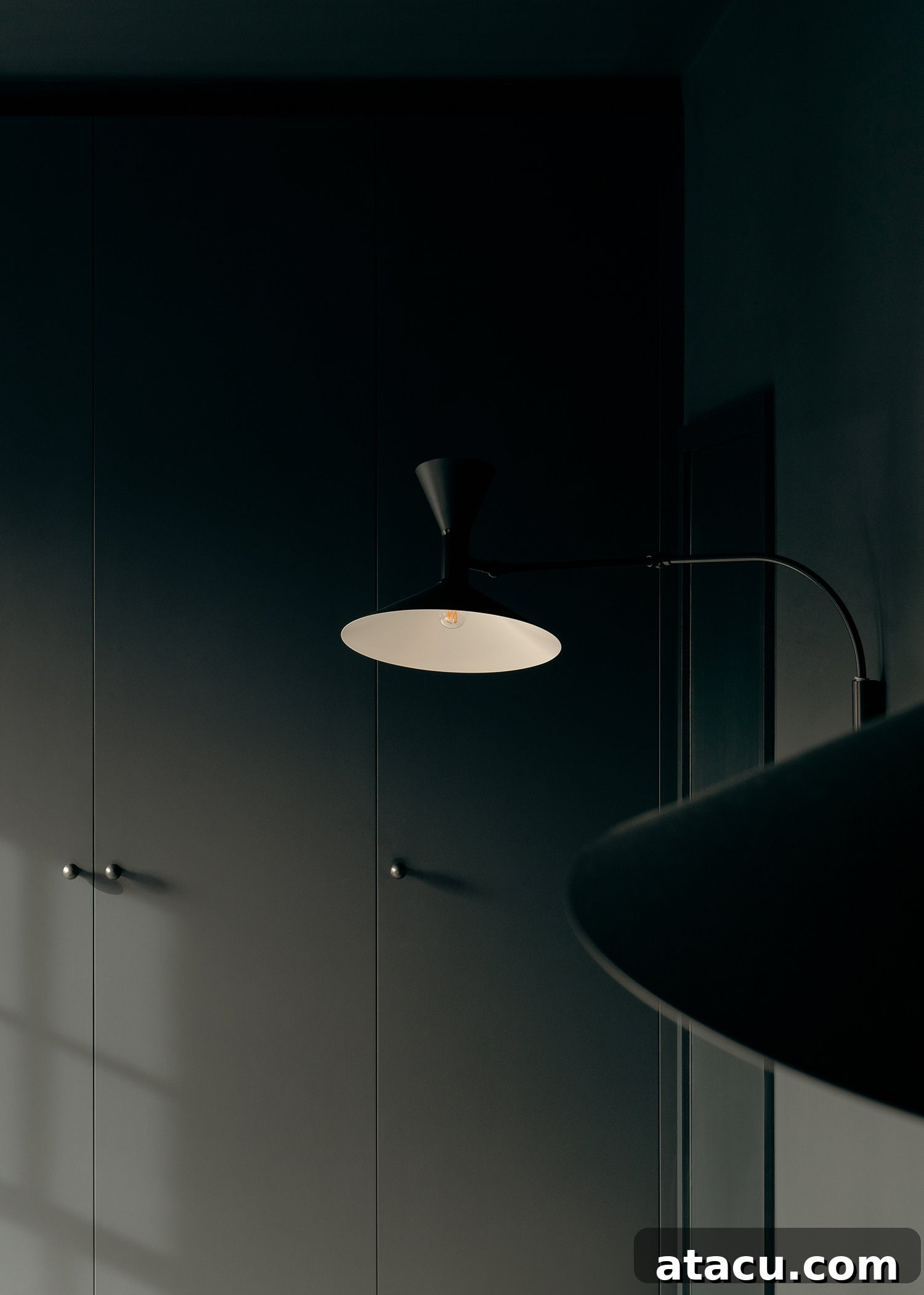 Dark, inviting bedroom with built-in wardrobes and a minimalist bedside lamp