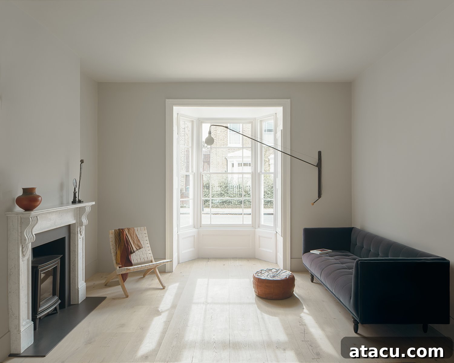Light-filled modern front room of the Victorian house with bay window and marble fireplace