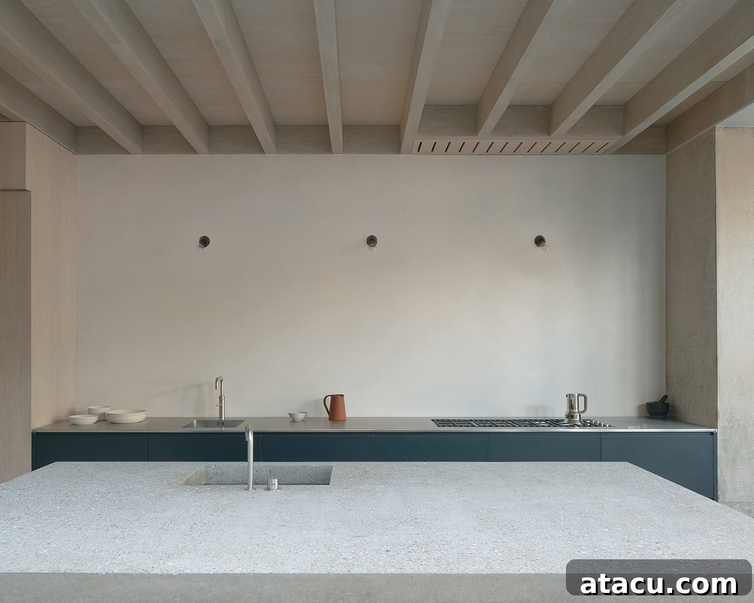 Modern kitchen with a concrete island, integrated appliances, and wooden ceiling beams