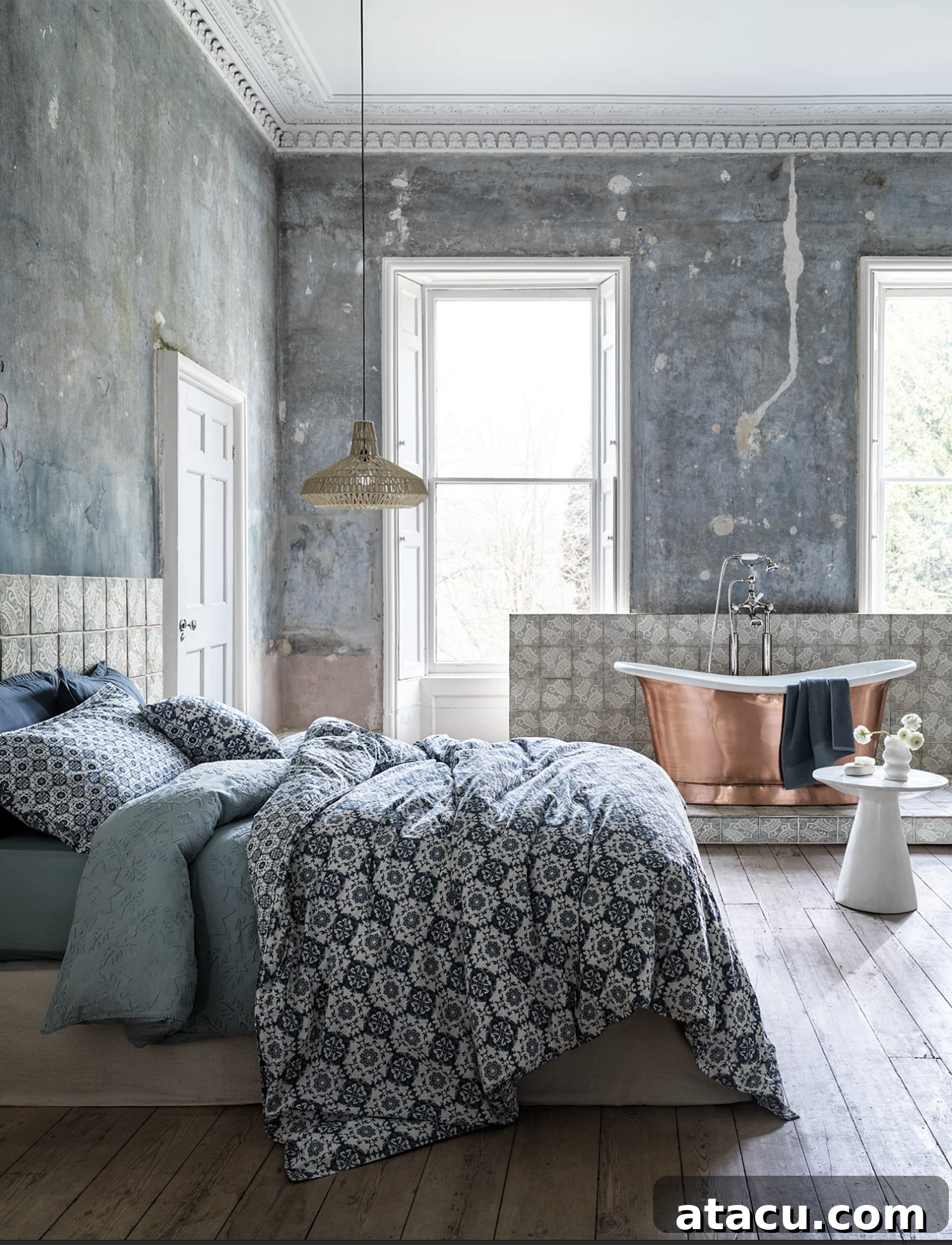 A faded interior with a copper bath and a bed with inky blue bedding.