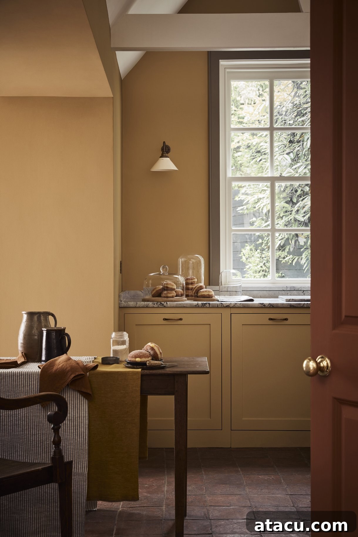 A cozy kitchen featuring Little Greene Bombolone on the walls and cupboard doors, a delightful peachy-pink shade that adds warmth and playfulness.