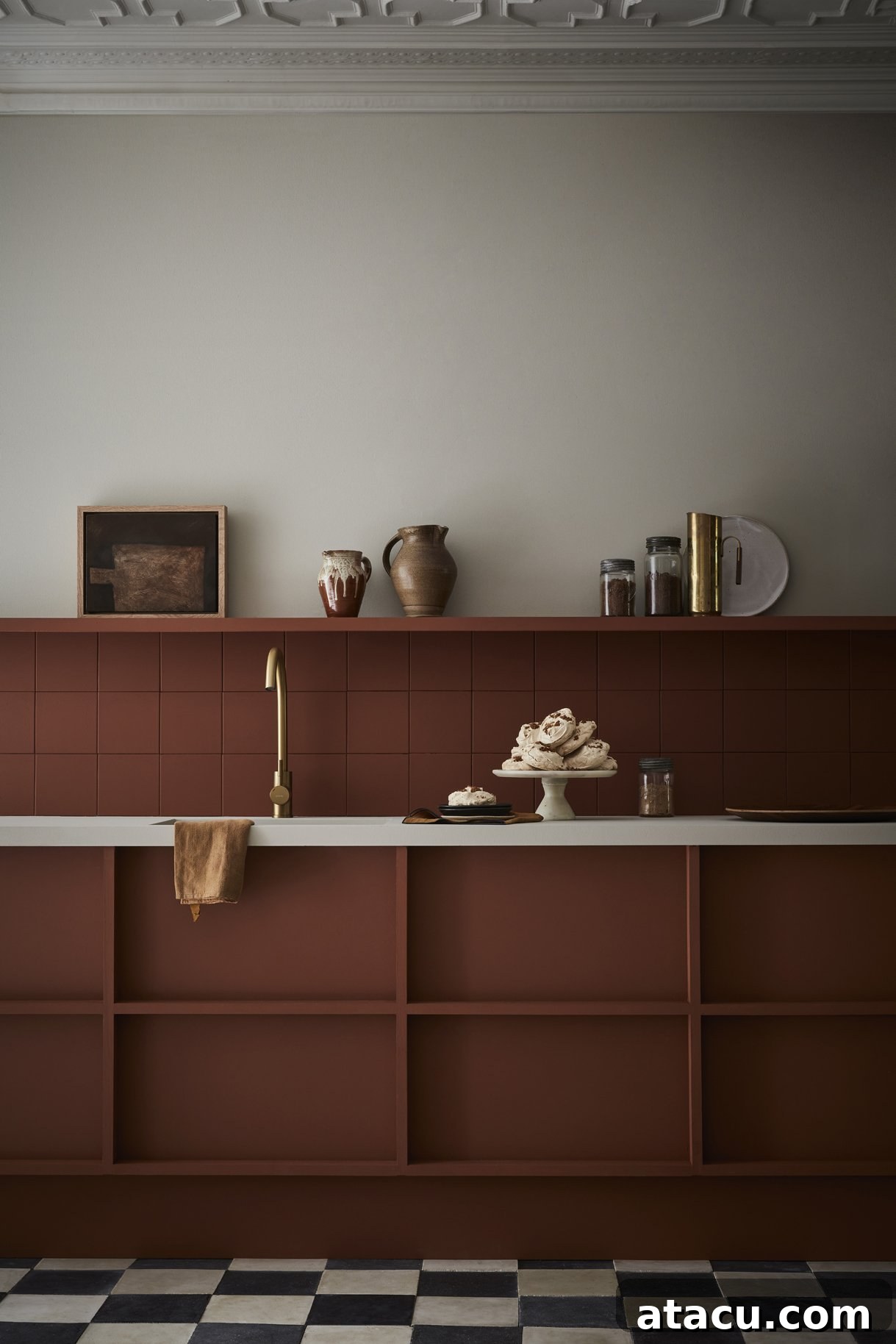 A stylish kitchen featuring units and tiled splashbacks in Little Greene Muscavado, a rich, dark brown, contrasted with Slaked Lime Dark on the wall and Slaked Lime on the cornice.