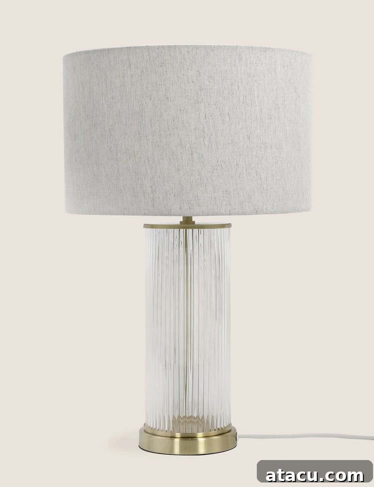 A ribbed glass table lamp with brass details and a neutral shade.