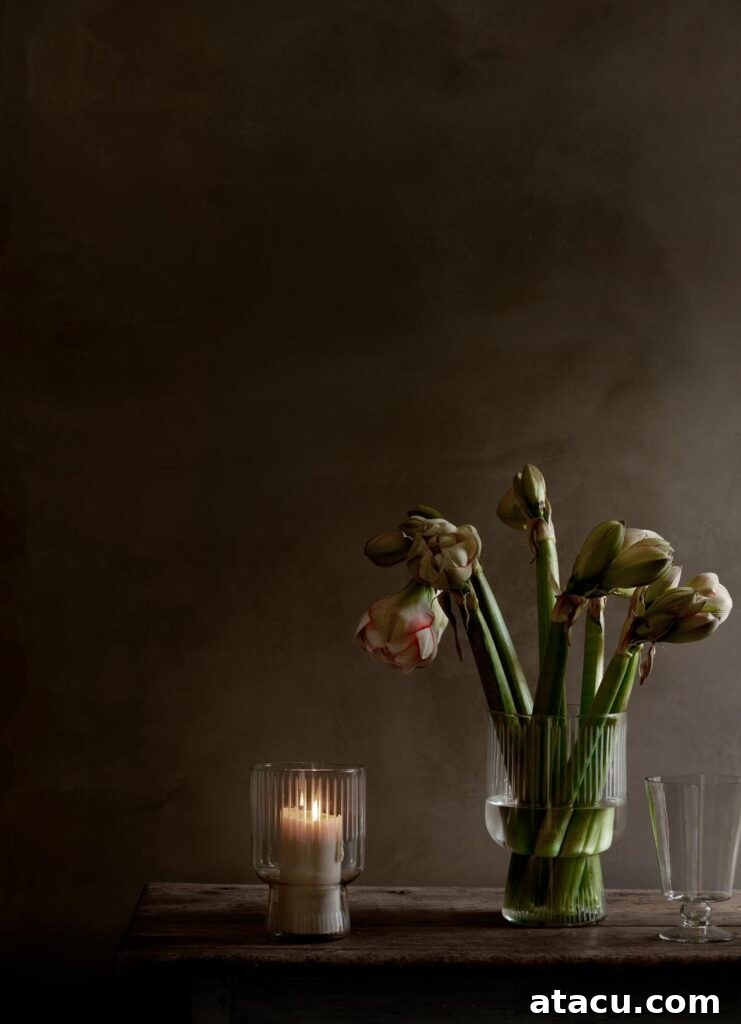 A vase of vibrant red amaryllis next to a glowing candle, set in a cozy festive ambiance.
