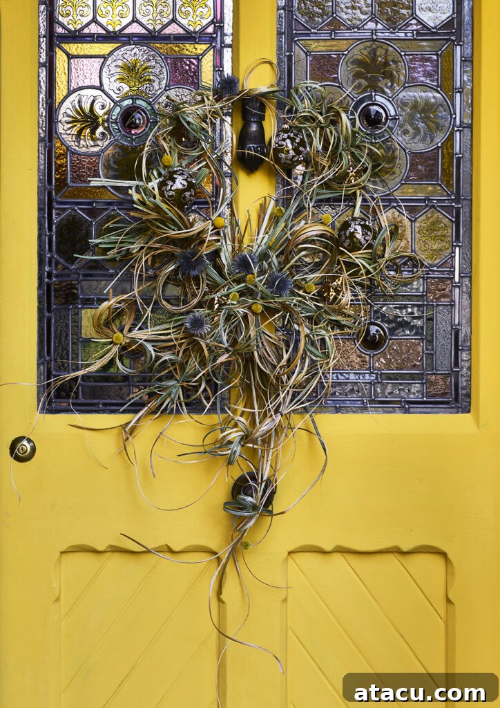 A rustic natural door wreath providing a striking contrast against a bright yellow front door, painted in 'Tilton' by Annie Sloan.