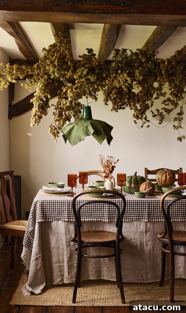 Embrace Autumn: Transform Your Home into a Warm Sanctuary 2 A cosy autumnal table setting with a garland of hops suspended about a table set with a linen tablecloth and tableware in autumnal hues.
