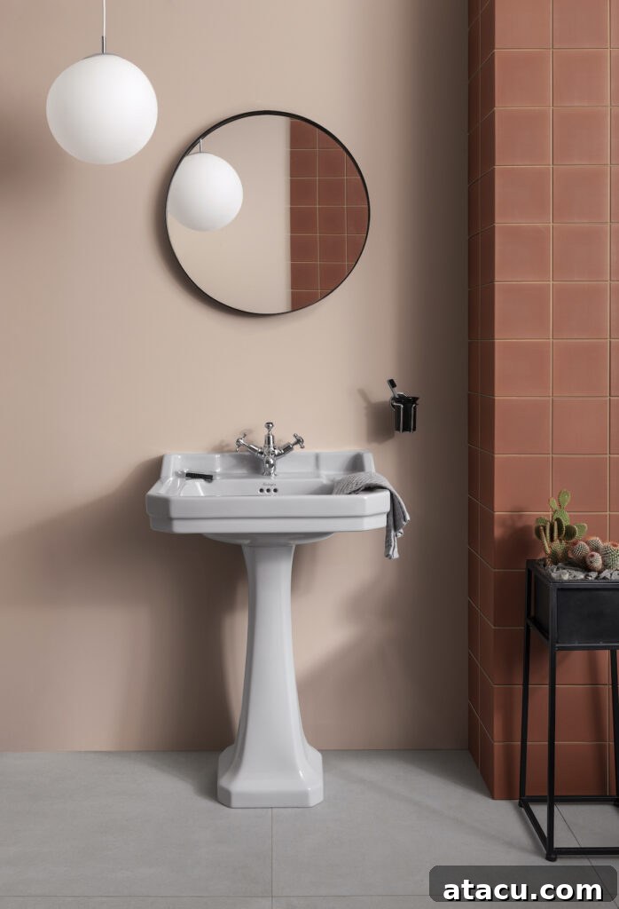 A stylish grey pedestal washbasin providing a striking contrast in a beautifully appointed pink bathroom.