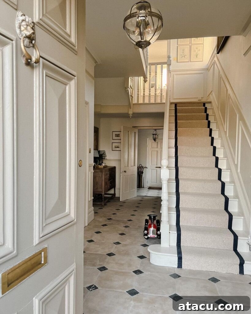Elegant hallway with a classic staircase, neutral tones, and black-accented runner, offering timeless hallway ideas for home design.