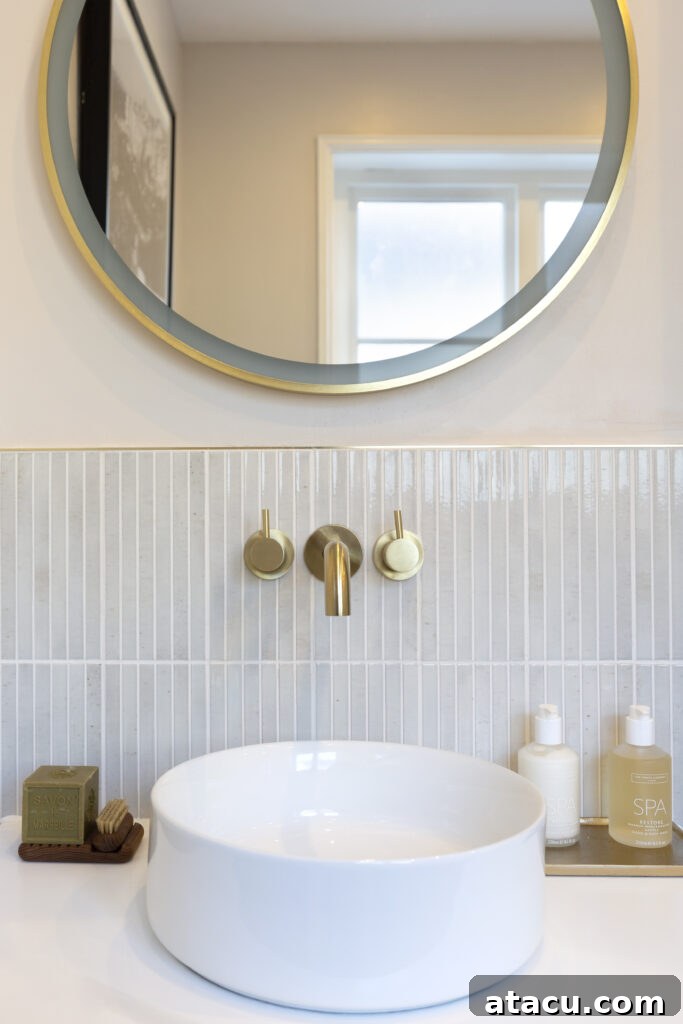 Vertically laid pearl gloss stick tiles creating an illusion of height in a compact modern bathroom.