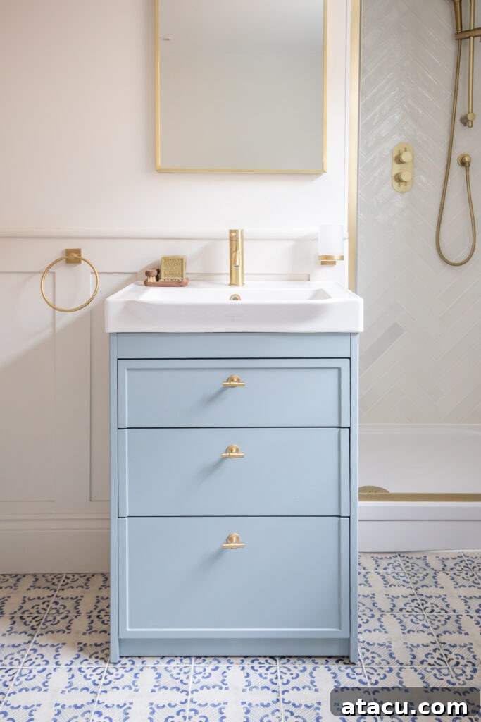 Patterned Pamplona Blanco porcelain floor tiles adding dynamism to a small bathroom with a pale blue vanity.