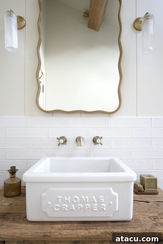 A pristine washbasin area featuring white gloss metro tiles and a large mirror above, expanding the small bathroom visually.