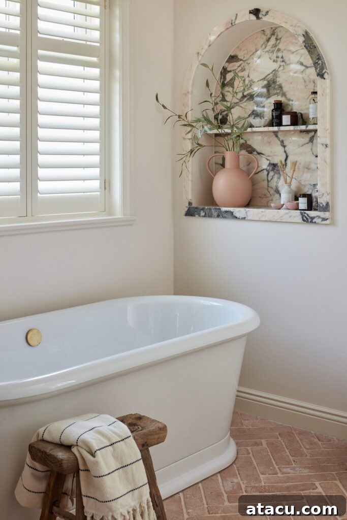 A small bathroom showcasing a freestanding bath and a striking terracotta parquet tiled floor, adding warmth and pattern.
