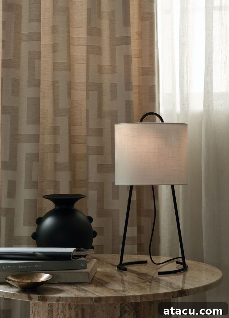 An elegant table lamp with a soft glow illuminating a sculptural ceramic vase, both resting on a minimalist tabletop. Neutral curtains in the background complete the refined and tranquil interior scene.