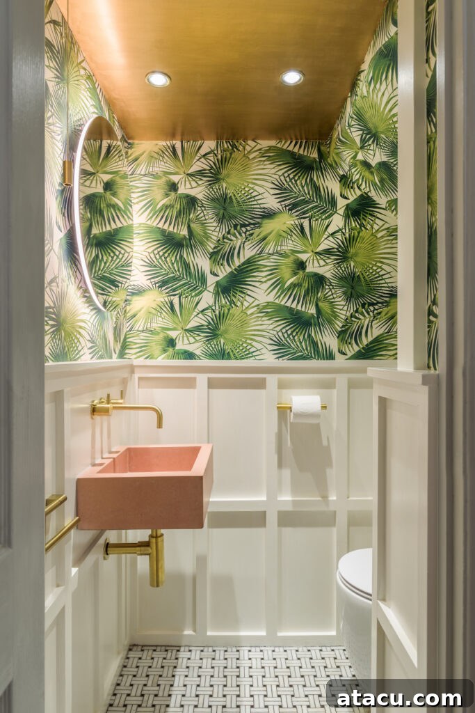 Compact cloakroom with basket weave marble floor tiles in a black and white pattern. The room features white panelling, tropical leaf wallpaper, a blush pink rectangular sink, and brass fixtures, with vibrant palm leaf wallpaper and a gold ceiling, creating a bold look.