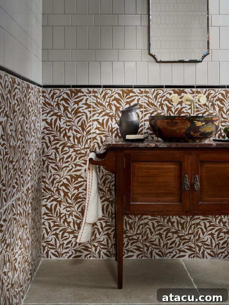 Elegant cloakroom featuring vintage-inspired design with botanical brown and white patterned tiles on the lower walls, paired with glossy white subway tiles above. A dark wood vanity with a decorative ceramic vessel sink adds warmth and character, complemented by an antique-style mirror and rustic stone flooring.