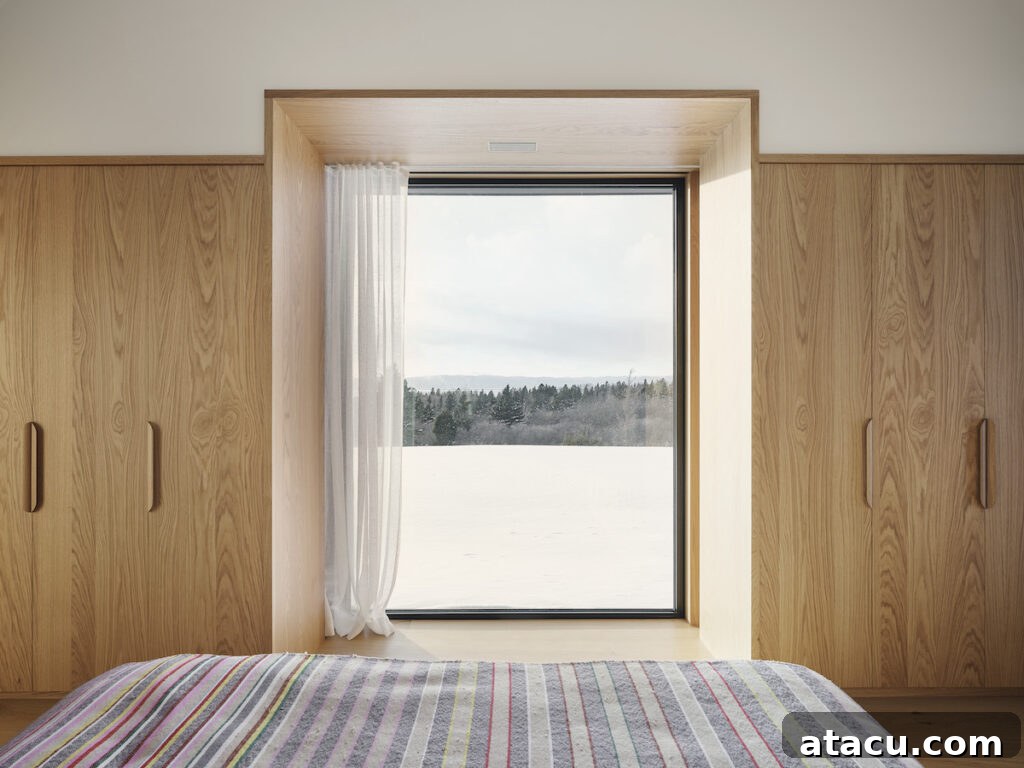 A picture window looking out onto a snowy scene in a modern minimalist oak bedroom.