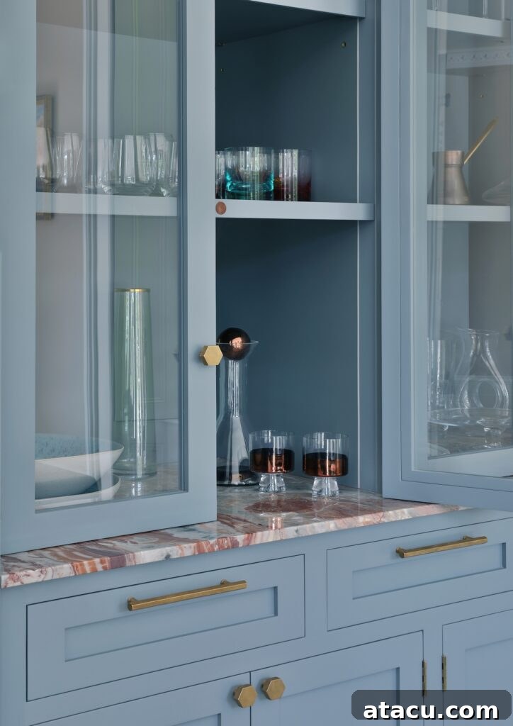 An opulent Shaker kitchen with painted blue cabinetry, Arabescato Rosso marble worktop and burnished brass handles.