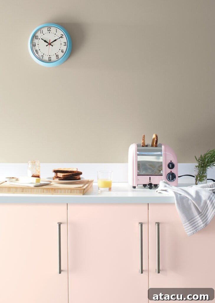 Retro-inspired kitchen design with soft pink painted cabinets, a blue clock, and a cozy breakfast setup.