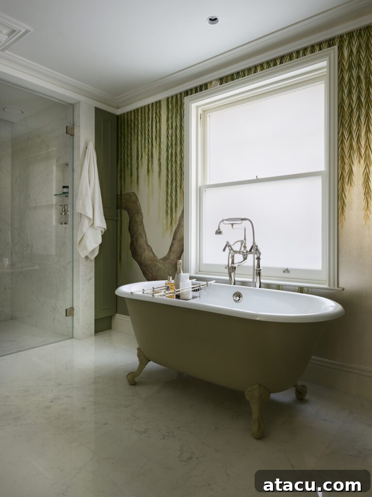 A luxurious Victorian style bathroom featuring a sage green cast-iron freestanding bath tub, large-format porcelain tiles, and elegant wallpaper.