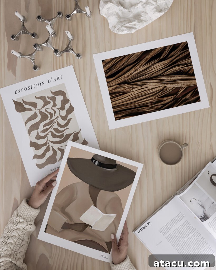 A selection of art prints on a wooden tabletop representing Mocha Mousse, the Pantone Colour of the Year for 2025.