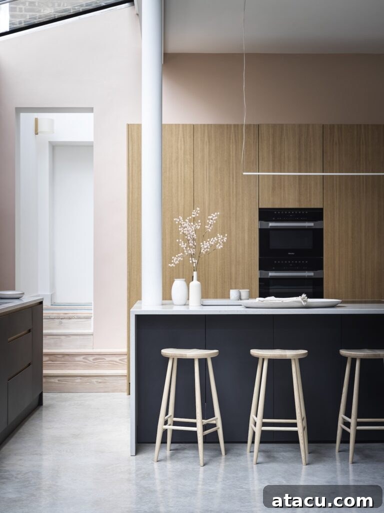 A modern kitchen with a kitchen island adjoined to a tall column pillar. Three ercol wooden counter stools sit underneath the island.