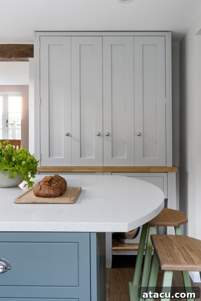 A curved kitchen island with quartz worktops and blue cabinets.