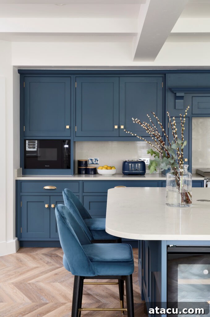 A blue kitchen with a kitchen island with white worktops and end seating.
