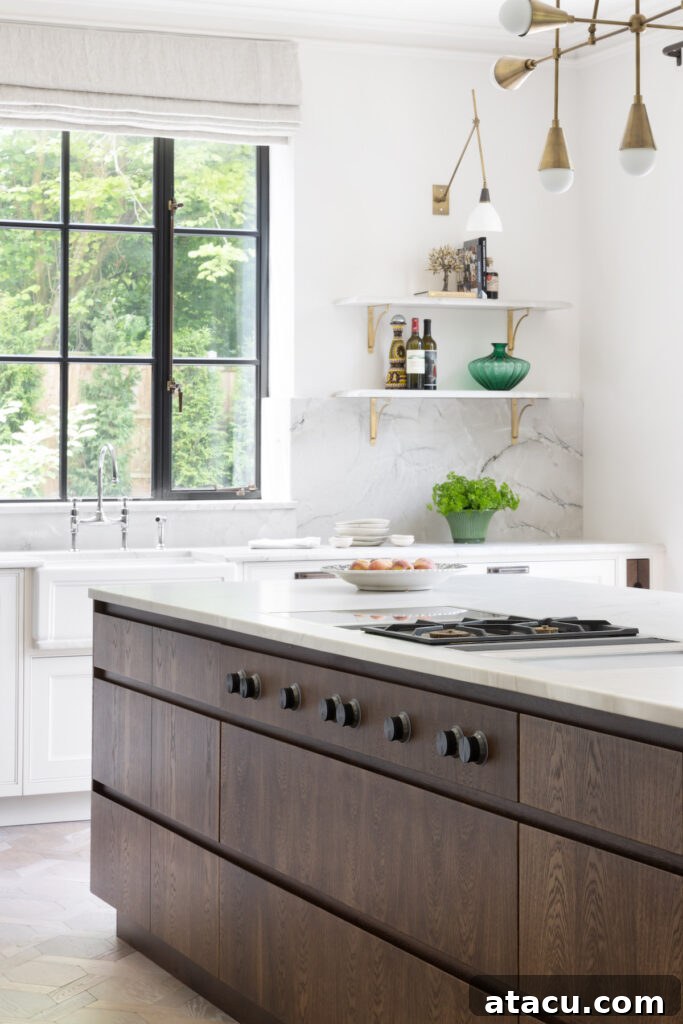 A modern kitchen with a dark wood kitchen island with hob and marble worktops.