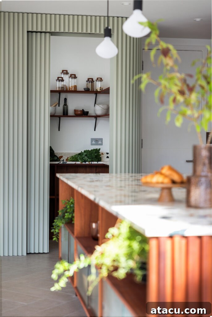 Sleek, modern kitchen featuring a hidden walk-in pantry concealed behind stylish fluted doors. Inside, the pantry boasts open wooden shelving and ample countertop space for organized food storage and preparation.