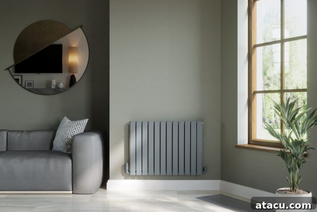 A contemporary living space featuring a compact gray radiator that complements the olive-toned walls. The room includes a cozy gray sofa with patterned cushions, a large geometric mirror, and a wooden-framed window that lets in natural light. A potted plant adds a fresh touch, making this a great example of home heating hacks that merge efficiency with modern style.