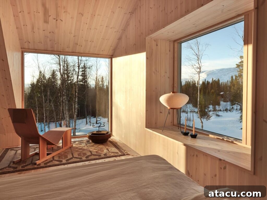 Serene mountain cabin home interior with large windows showcasing snowy forest views and warm wooden paneling, creating a cozy atmosphere.