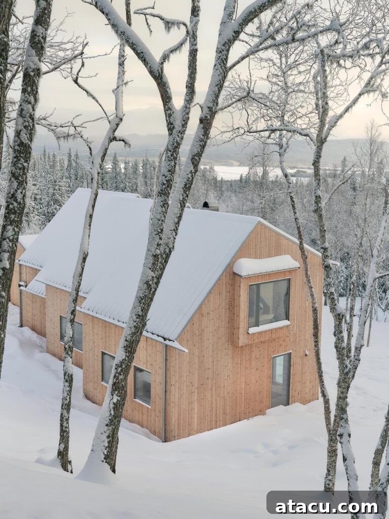 A snow-covered modern mountain cabin retreat surrounded by frosted trees in a serene, crisp winter landscape, showcasing its blend with nature.