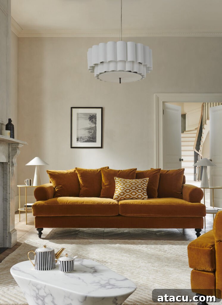 A sophisticated living room with a mustard velvet sofa, neutral walls, a sculptural white chandelier, and a marble coffee table with striped teaware.