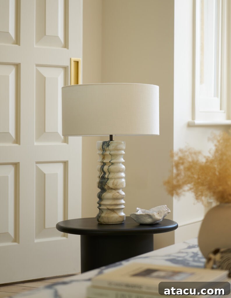 A table lamp with a drum shade and marble base in an elegant room.