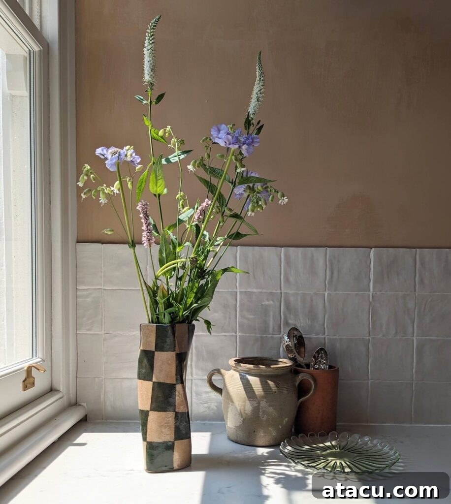 A check twist vase filled with flowers standing next to a window.