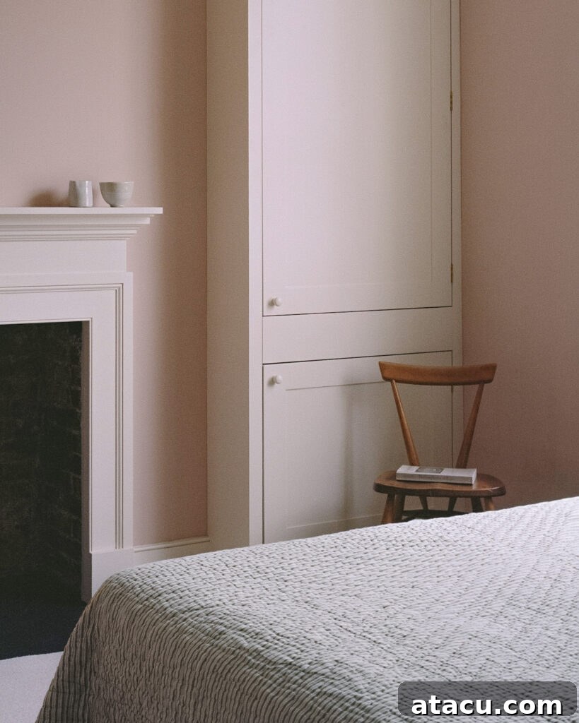 A close-up of a bedroom in a Georgian home renovation with soft pink walls, a white fireplace, and built-in cabinetry.