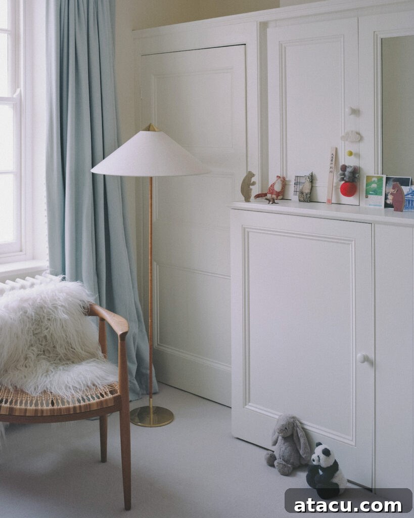 A cozy children's bedroom in a Georgian home renovation with built-in storage, soft blue curtains, and wooden furnishings.