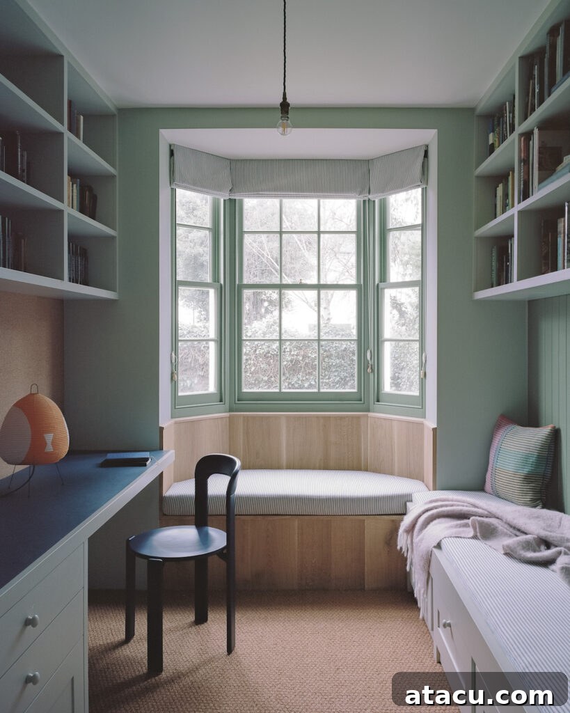 A cozy study nook in a Georgian home renovation with built-in bookshelves, a bay window seat, and soft green tones.