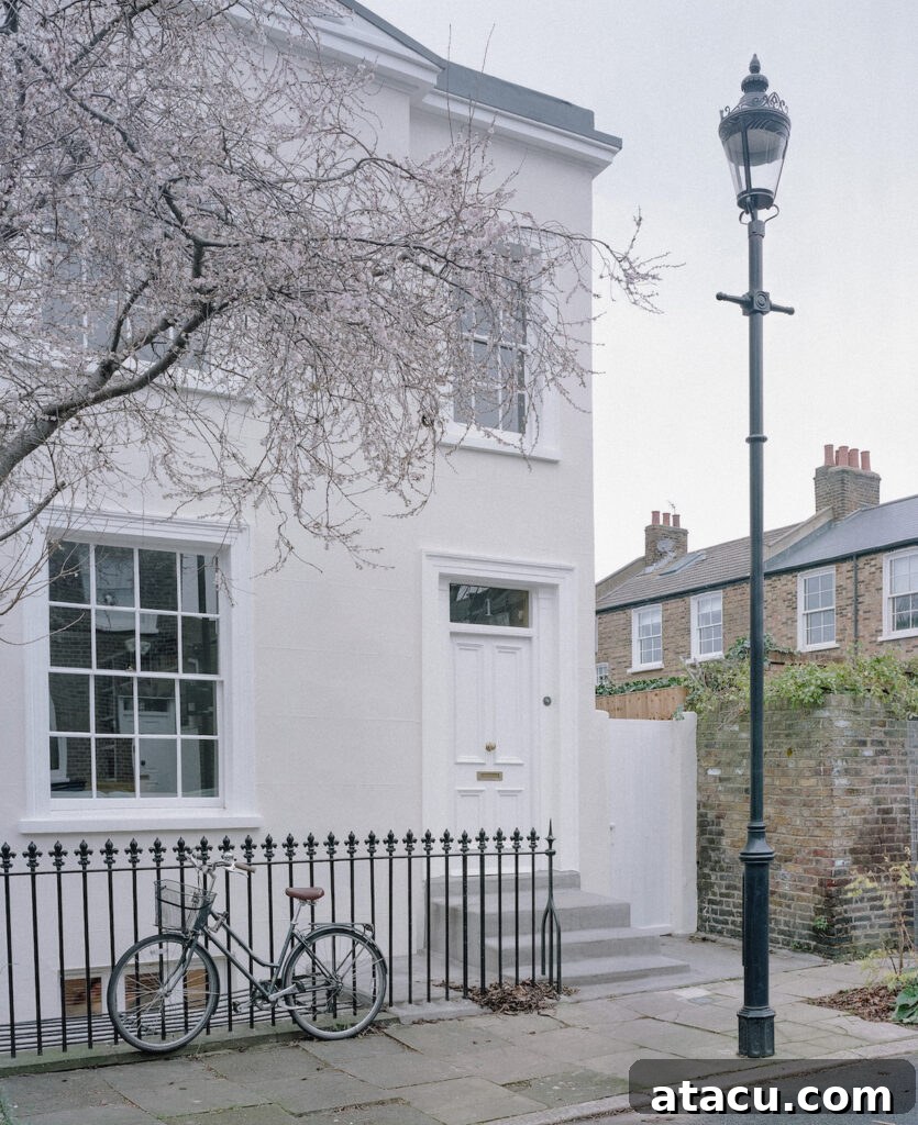 A Georgian home renovation featuring a soft pink exterior, black iron fencing, and a vintage bicycle parked outside.