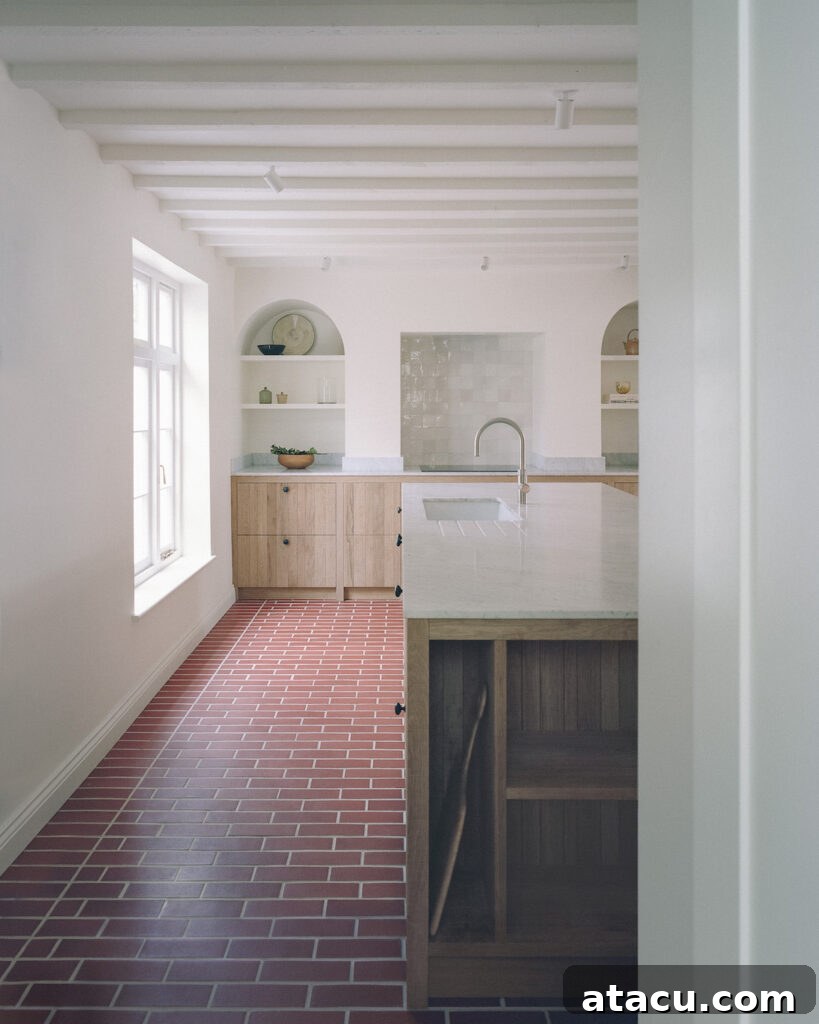 A renovated Georgian kitchen with exposed beams, brick flooring, and wood cabinetry with marble countertops.