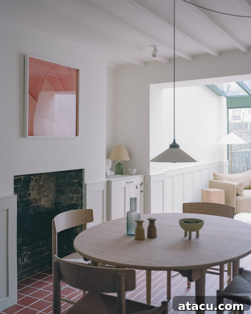 A dining area in a Georgian home renovation with a wooden table, brick flooring, and a view into the sunroom.