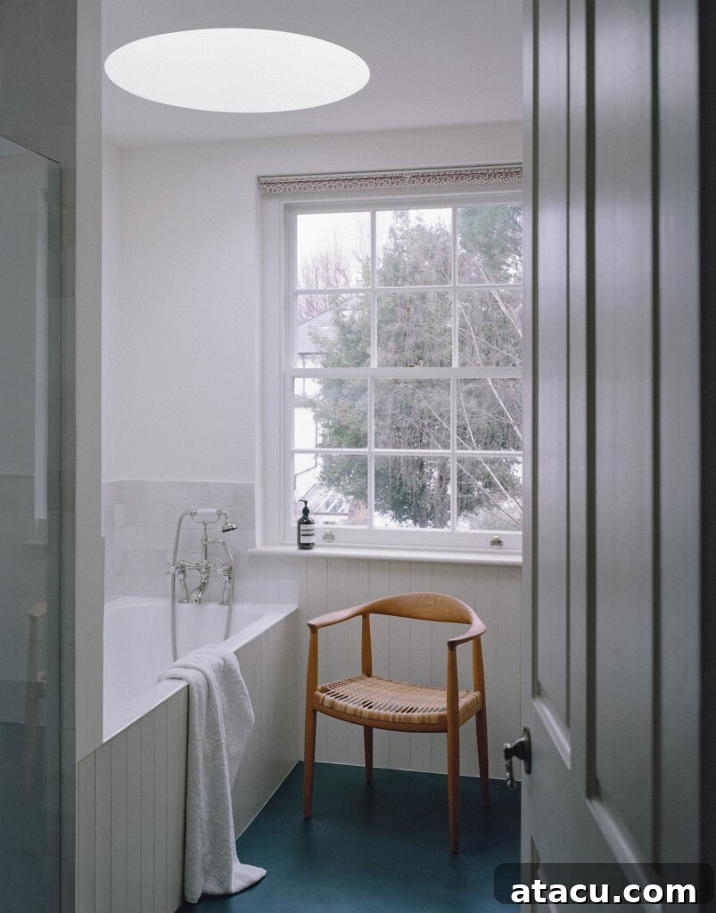 A bright bathroom in a Georgian home renovation featuring a bath, a woven chair, and a skylight for natural illumination.