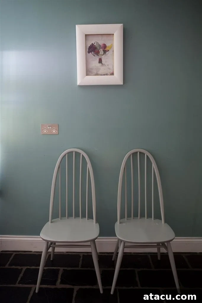 Curated Duck Egg Blue Paint Colors by Top Brands 8 Two elegant chairs against a wall painted in Dix Blue by Farrow and Ball, showcasing its deep, muted character and warm undertones.
