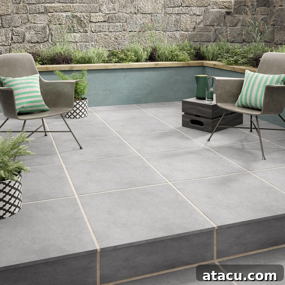 Mastering Outdoor Porcelain Tile Cleaning for a Flawless Finish 3 Light grey porcelain patio tiles with modern chairs and potted plants in a garden courtyard.
