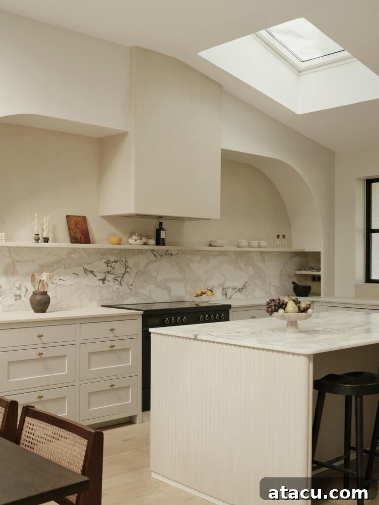 Modern kitchen with a striking marble backsplash, a beautifully sculpted range hood, and an overall palette of soft, neutral tones.