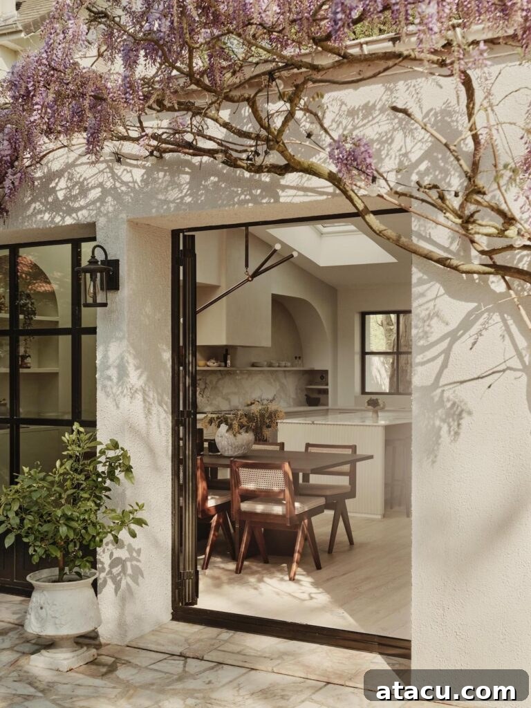 View into an open dining area from an inviting patio, beautifully framed by cascading blooming wisteria overhead.