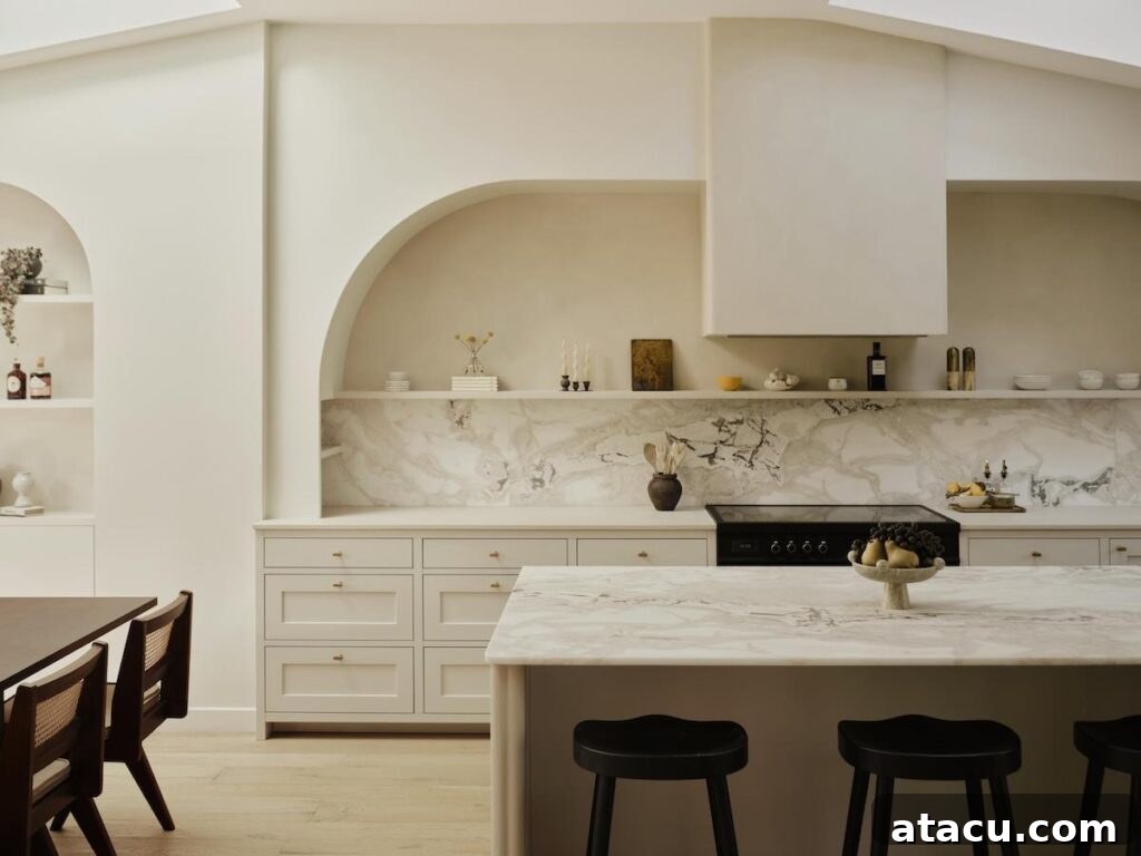 Spacious open kitchen with bespoke shaker cabinetry, a generous marble island, and decorative arched shelving units.