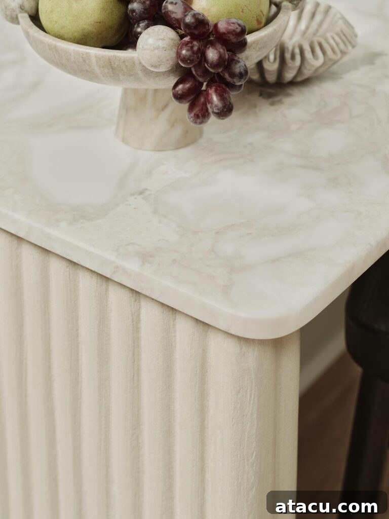 Close-up detail of a fluted marble kitchen island, showcasing the tactile richness of the polished stone surface with a decorative fruit bowl.