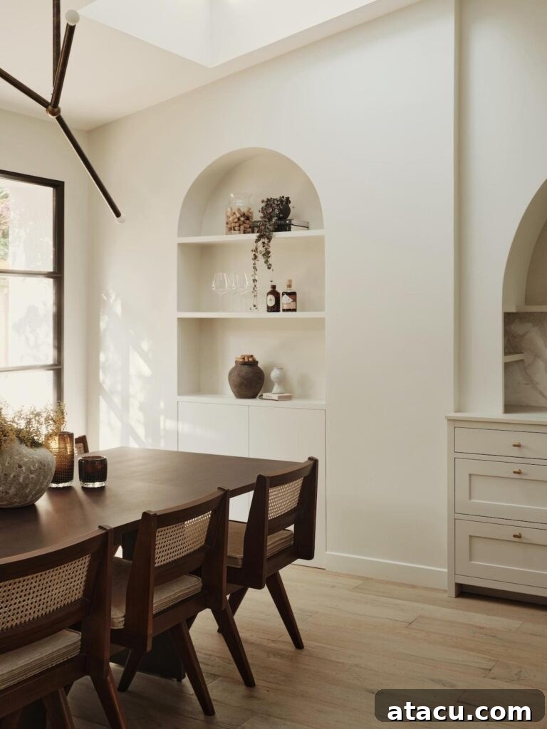 Minimalist dining room with ample natural light, featuring elegant built-in arched shelves and cabinetry in a cohesive design.